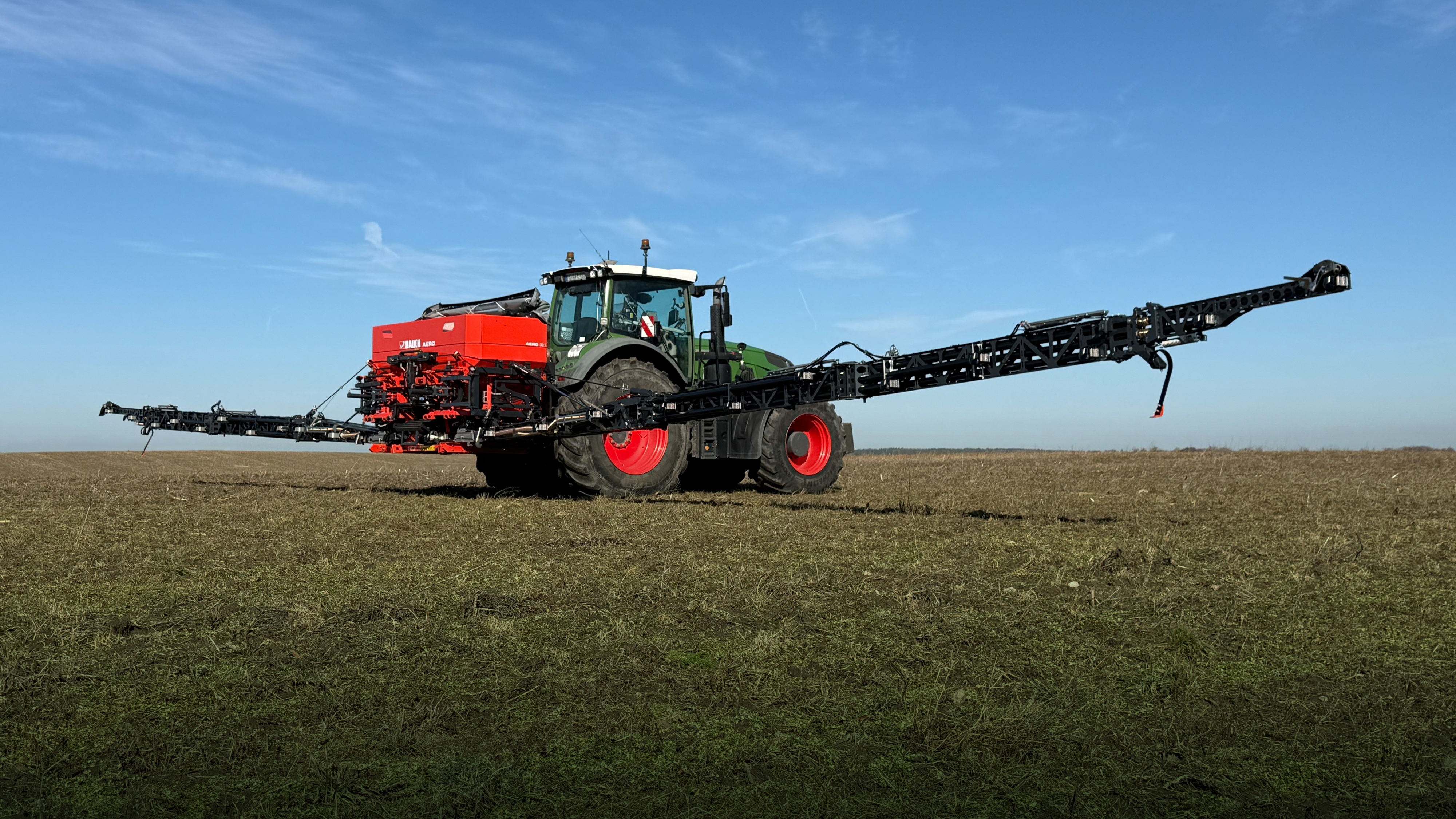 Tractor with attached fertilizer spreader applying mineral fertilizer.